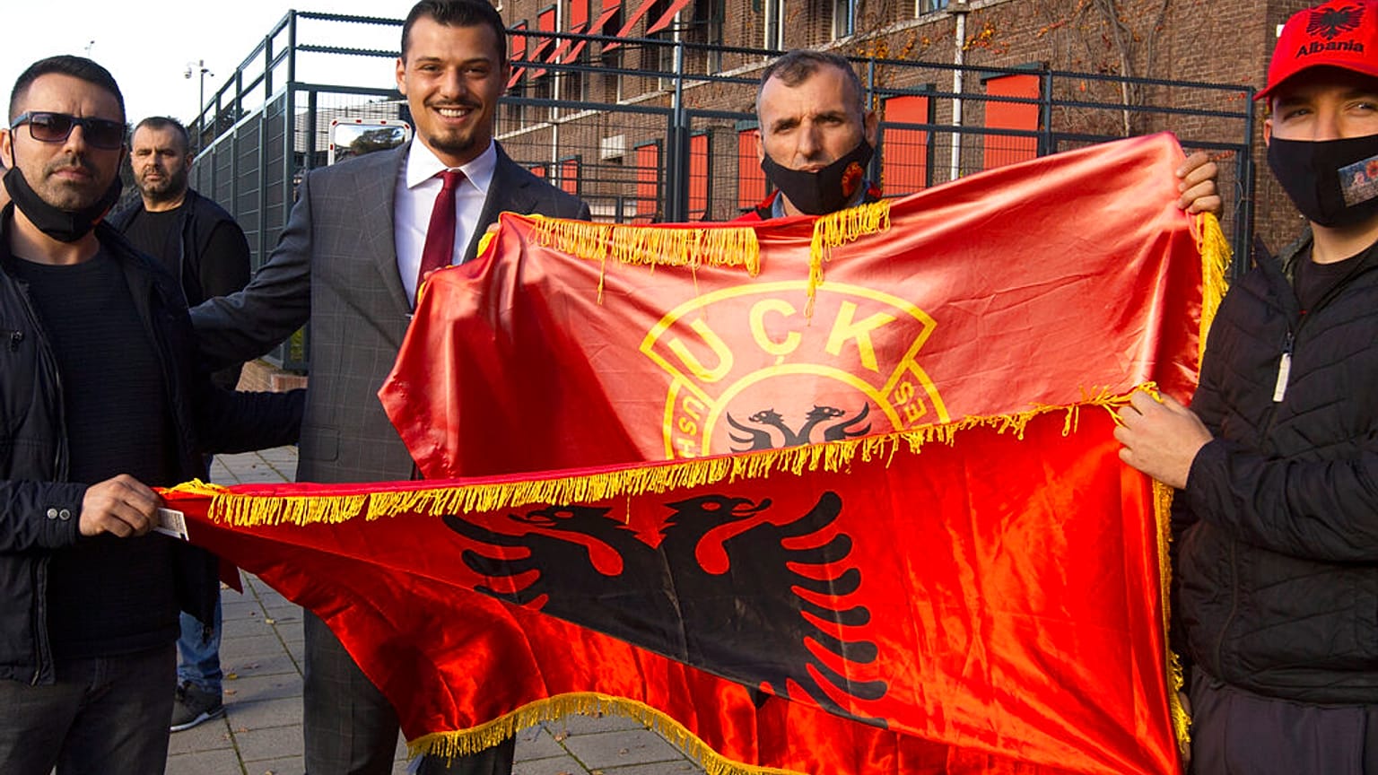 Endrit Thaci, third left, son of Hashim Thaci, poses outside the court building where Thaci is to face charges including murder, torture and persecution.