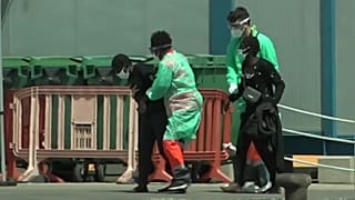 Dos migrantes son ayudados por sanitarios tras llegar a Tenerife en patera
