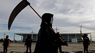 متظاهر يرتدي زي الموت أمام قصر بلانالتو الرئاسي احتجاجًا على تعامل الرئيس مع جائحة كوفيد-19 في برازيليا، 26 مارس 2021