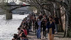 People stroll along the Seine river bank in Paris, where hospitals are under significant pressure from COVID-19 patients