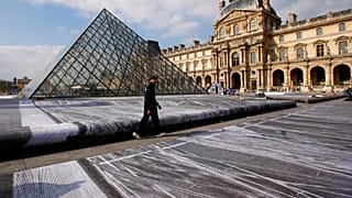 FILE: French street artist JR walks in the courtyard of the Louvre Museum near the glass pyramid designed by architect Leoh Ming Pei, in Paris, 27th March 2019