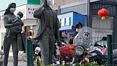 Statues along a street are seen with masks placed on them as a WHO mission team visits Wuhan in central China's Hubei province on Feb. 9, 2021.