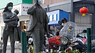 Statues along a street are seen with masks placed on them as a WHO mission team visits Wuhan in central China's Hubei province on Feb. 9, 2021.