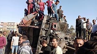 يتجمع مصريون حول عربات قطار مشوهة في موقع حادث قطار في مدينة سوهاج بجنوب مصر - 26 آذار / مارس 2021