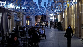 People sit and drink, outside a coffee shop, in Faneromeni square in the capital Nicosia, Cyprus