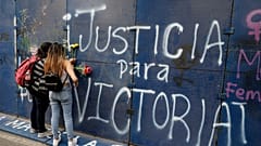Jóvenes mexicanas colocan flores ante un grafiti que pide 'Justicia para Victoria' en Quintana Roo, México