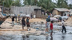 People carry bags of carbon on the shores of the Paquitequete neighborhood where sailing boats are expected to arrive with people displaced from Palma