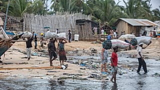People carry bags of carbon on the shores of the Paquitequete neighborhood where sailing boats are expected to arrive with people displaced from Palma