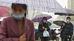 People wearing face masks to protect against COVID-19 wait in the rain to pick up children from a school in Wuhan.