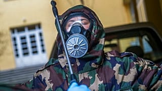 A Hungarian soldier wearing a hazmat suit clears himself after completing the disinfection of a combined kindergarten and elementary school in Budapest, Hungary