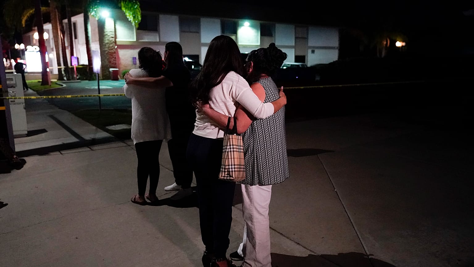 Unidentified people comfort each other as they stand near a business building where a shooting occurred in Orange, Calif., Wednesday, March 31, 2021