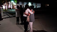 Unidentified people comfort each other as they stand near a business building where a shooting occurred in Orange, Calif., Wednesday, March 31, 2021