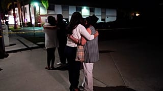 Unidentified people comfort each other as they stand near a business building where a shooting occurred in Orange, Calif., Wednesday, March 31, 2021