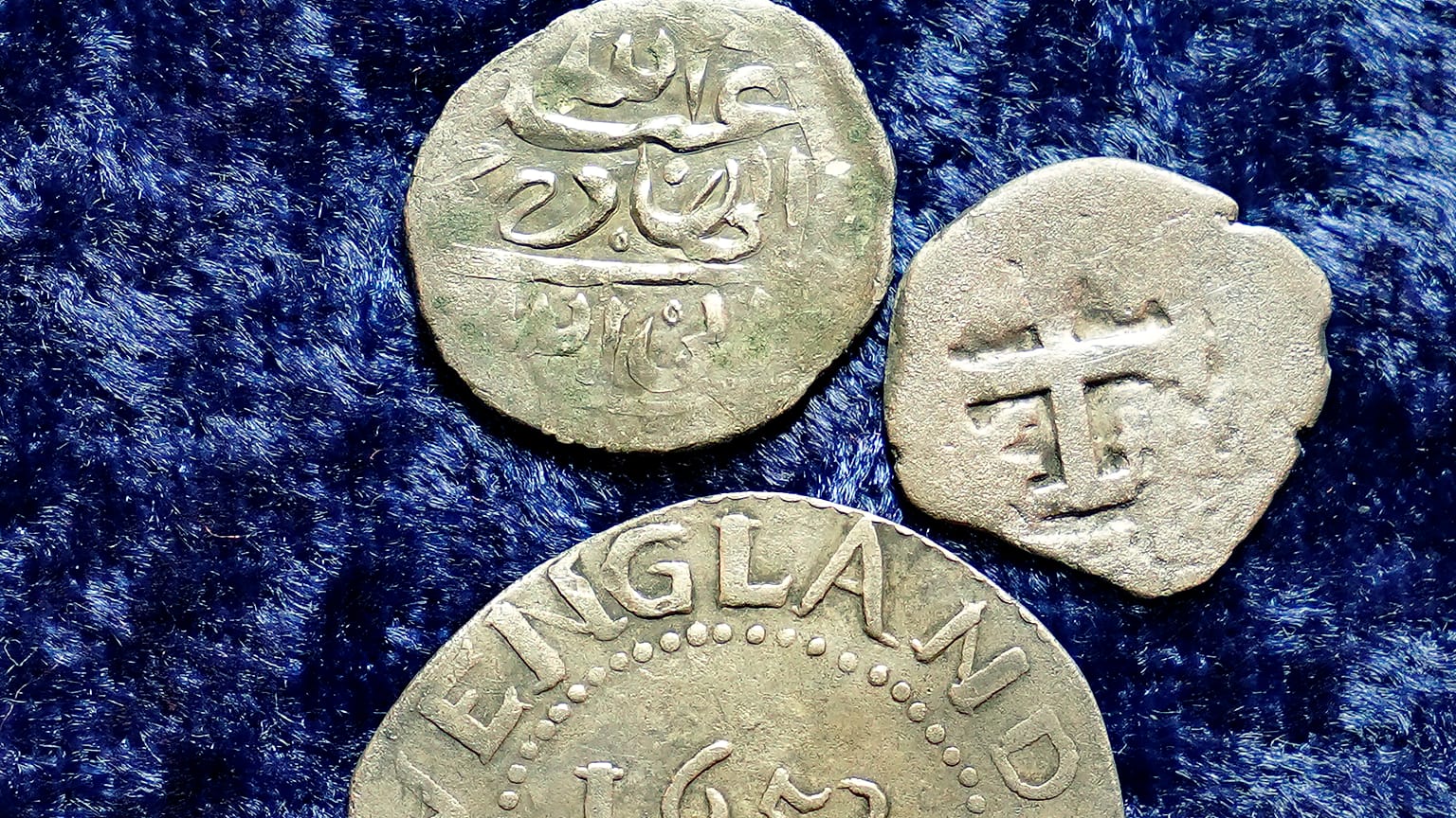 Egy 1693-ban Jemenben vert érme, egy 1652-es Oak Tree Shilling Massachusettsből és egy spanyol félreálos érme