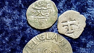 Egy 1693-ban Jemenben vert érme, egy 1652-es Oak Tree Shilling Massachusettsből és egy spanyol félreálos érme
