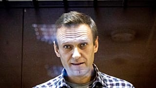 In this photo taken on Saturday, Feb. 20, 2021, Russian opposition leader Alexei Navalny looks at photographers standing behind a glass of the cage in the Babuskinsky District