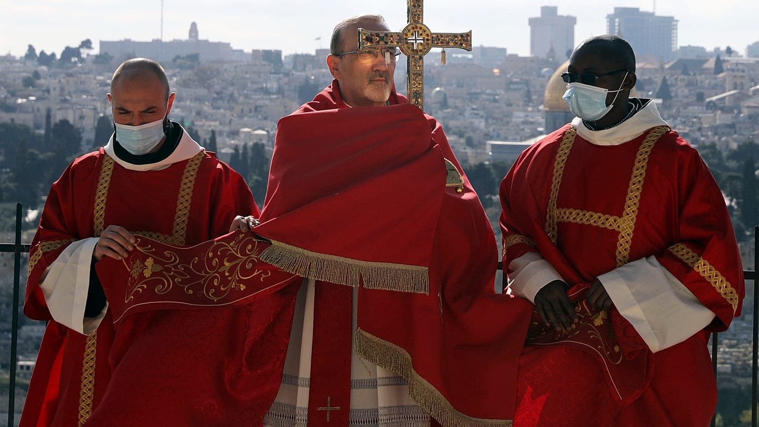 Latin Patriarch of Jerusalem Pierbattista Pizzaballa, center, holds a cross on Palm Sunday on the Mount of Olives in Jerusalem, March 28, 2021.