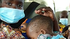 Uma mulher com uma criança ao colo é levada de avião de Palma para Pemba, em Moçambique
