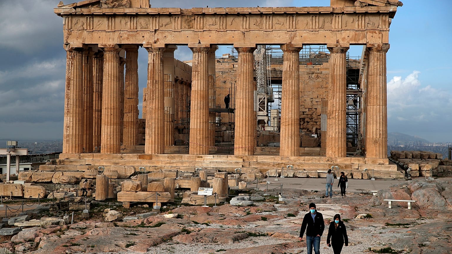 The first visitors wearing face masks to protect against the spread of COVID-19, walk atop of Acropolis hill, in Athens, March 22, 2021.