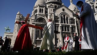 Archbishop Michel Aupetit, left, carries the holy cross at the Way of the Cross ceremony as part of the Holy Easter celebration, in the Sacre Coeur basilica, in Paris, France.