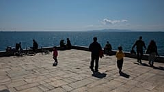 People enjoy a sunny day at a square at Piraeus port town near Athens