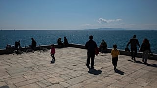 People enjoy a sunny day at a square at Piraeus port town near Athens