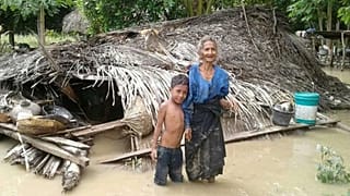 Une villageoise et son petit-fils devant leur maison endommagée dans le village de Haitimuk, en Indonésie, également touchée par les inondations le 4/04/21
