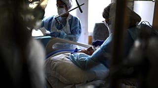 Nurses tend to a Covid-19 patient under respiratory assistance lying unconscious in the intensive care unit of the Hopital Prive hospital in Antony, France, April 2, 2021.