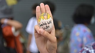 A protester raises a decorated Easter egg along with a symbol of resistance during a protest against the military coup on Easter Sunday, April 4, 2021 in Yangon, Myanmar. 