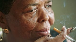 Singer Cesaria Evora, known as the "Barefoot Diva", smokes a cigarette during an interview at her home in Cape Verde in 2000.