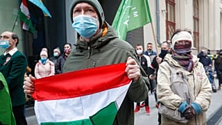 A man holds a Hungarian flag during a protest in Budapest, Hungary, Monday, March 15, 2021.