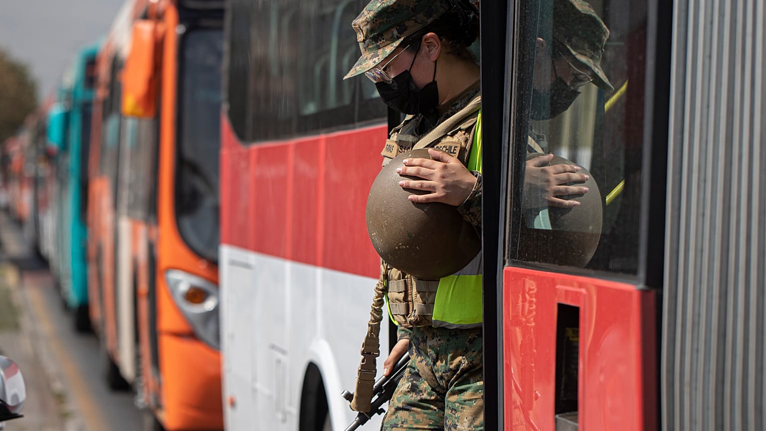 Una soldado sale de un autobús en un puesto de control en Santiago de Chile tras verificar los permisos de tránsito de los pasajeros.