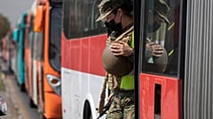 Una soldado sale de un autobús en un puesto de control en Santiago de Chile tras verificar los permisos de tránsito de los pasajeros.