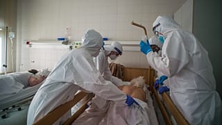 Védőfelszerelést viselő orvosok hasra fordítanak egy beteget a fővárosi Honvédkórház koronavírus- osztályán