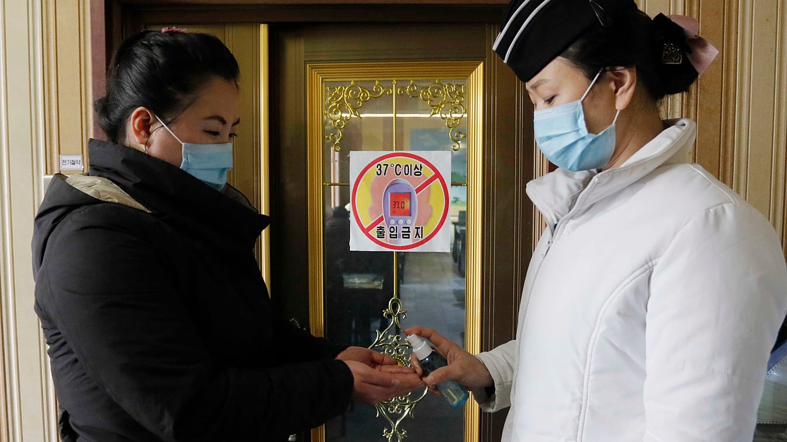 A staff member, right, of the Pongnam Noodle House disinfects the hands of a woman coming into its restaurant in Pyongyang, North Korea.