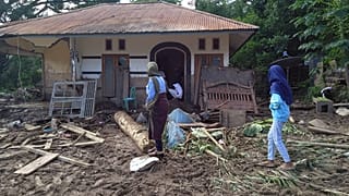 Indonesian women walk past a house damaged by flood in Waiwerang, on Adonara Island, East Nusa Tenggara province, Indonesia, Tuesday, April 6, 2021.