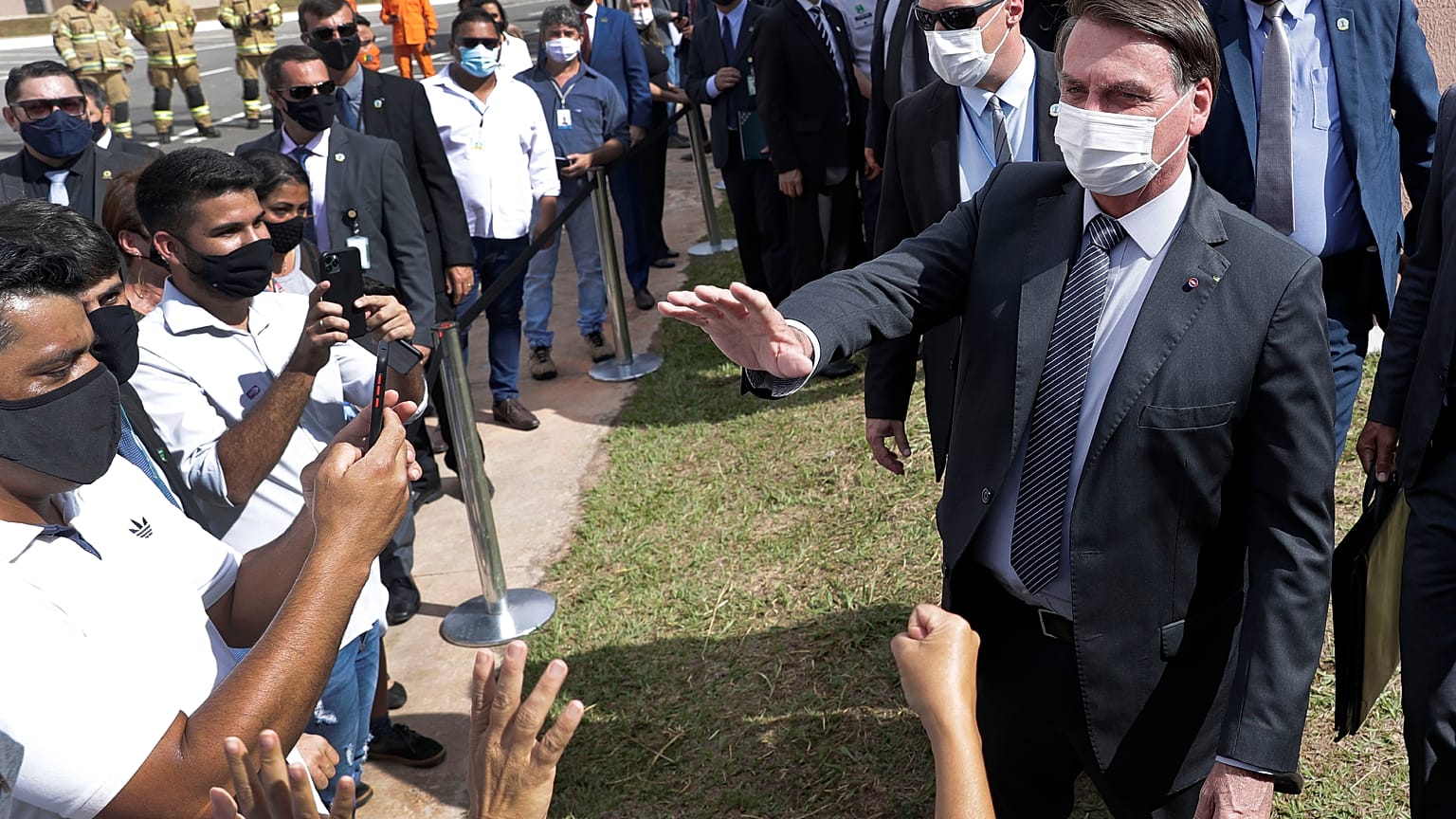 Wearing a mask, Brazil's President Jair Bolsonaro greets people in a neighborhood of Brasilia, Monday, Apr. 5, 2021. 