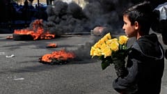 Un bambino siriano guarda i manifestanti che bruciano pneumatici per bloccare una strada principale durante una manifestazione a Beirut 