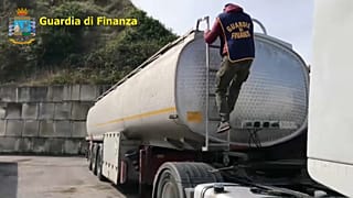 Un agente della GdF si arrampica su un'autocisterna
