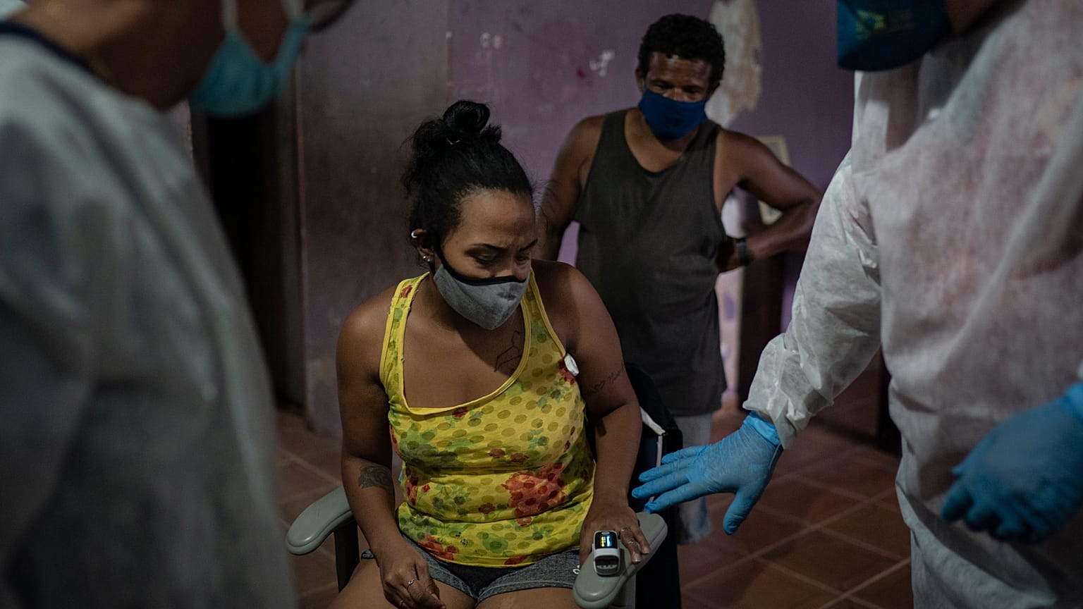 Mobile Emergency Care Service (SAMU) worker Elias Anjo, right, checks a patient suspected of having COVID-19 at her house in Duque de Caxias, Brazil.