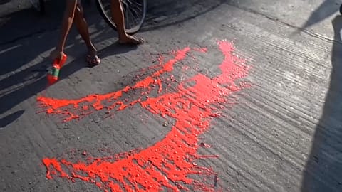 Anti-coup protestors splashing red paint on street to symbolise the blood shed by their movement