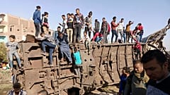 Egyptians gather around mangled train carriages at the scene of a train accident that killed at least 18 people and wounded 200 others including children, in Sohag, Egypt