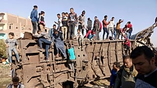 Egyptians gather around mangled train carriages at the scene of a train accident that killed at least 18 people and wounded 200 others including children, in Sohag, Egypt