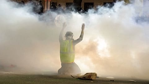 Protester in foreground engulfed in tear gas