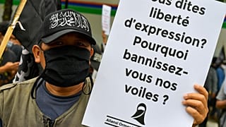 متظاهرون مسلمون يرفعون لافتات خلال مظاهرة مناهضة للرئيس الفرنسي إيمانويل ماكرون.