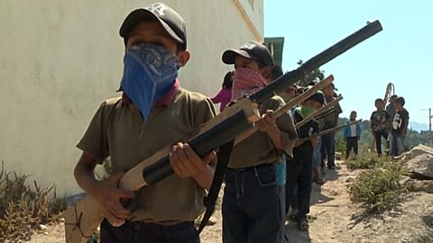 Child wearing a mask holds a replica rifle 
