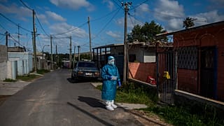 Un sanitario espera antes de hacer un test de covid en un barrio de Montevideo
