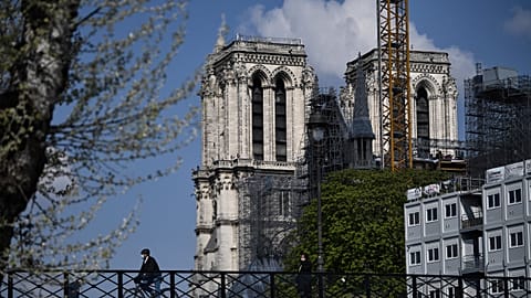 A cyclist ride his bike over the Pont de l'Archeveche (Archbishop's Bridge), past the Notre-Dame de Paris cathedral, on April 14, 2021, during the reconstruction work