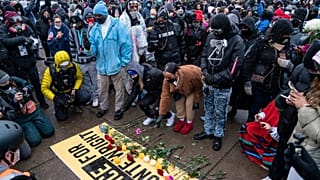 Flowers are placed on a banner as demonstrators gather outside the Brooklyn Center Police Department on April 13, 2021, to protest the shooting death of Daunte Wright.