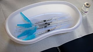 Syringes and a vial of the AstraZeneca vaccine sit on a general practitioners' table in Amsterdam.